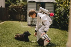 Boy in astronaut suit playing with his dog