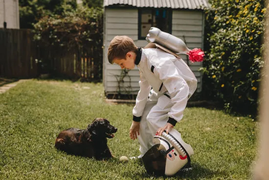 Boy in astronaut suit playing with his dog